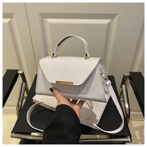 Détail du sac blanc en cuir crocodile avec fermoir doré et poignée élégante