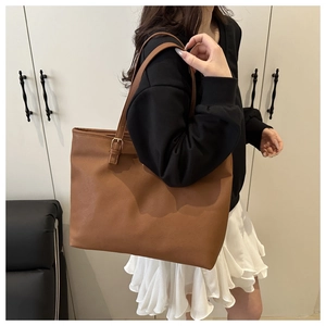 Detailed view of brown leather tote bag with adjustable metal buckle strap on shoulder