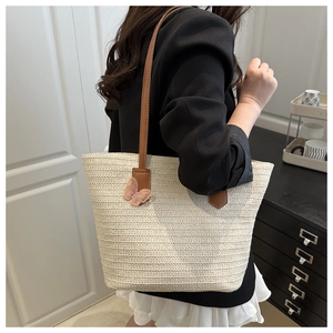 Detail of woven straw tote bag with 3D pink butterfly embroidery and brown leather strap
