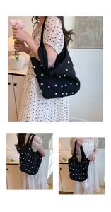 Detail of black knit tote bag with colorful pearls on a floral dress background