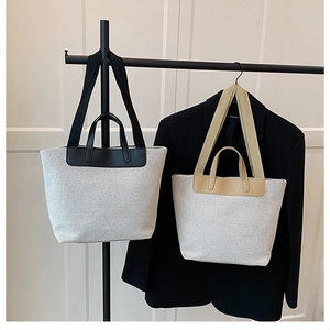Detail view of canvas tote bags with black and beige trims and sturdy leather straps