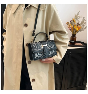 Detail of a chic leopard print crossbody bag with gold lock on a classic trench coat