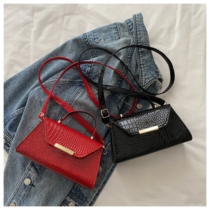 Vue de dessus de sacs bandoulière rouges et noirs en cuir croco avec boucles dorées