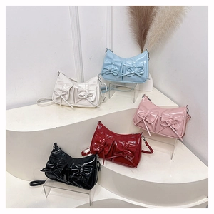 Detail of five glossy patent leather handbags with bow decorations and pockets in various colors