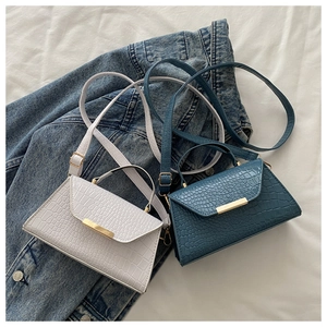 Détail du sac bandoulière à motif crocodile avec boucle dorée sur tissu en jean