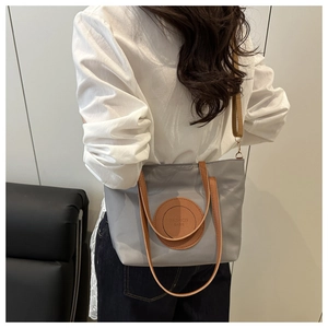 Detail of gray nylon tote bag with brown leather straps and fashion bags logo patch