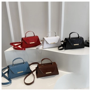 Détail de sacs à main à motif crocodile colorés avec fermoirs dorés sur marches blanches
