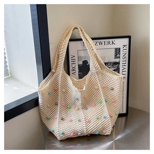 Detail of crochet tote bag with colorful beads and vintage handmade texture on a silver table