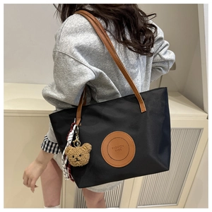 Close-up of durable black nylon tote bag with leather strap and cute plush bear charm