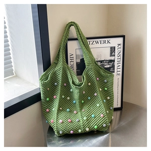 Detail of green woven cotton tote bag featuring colorful bead accents and manual knit texture