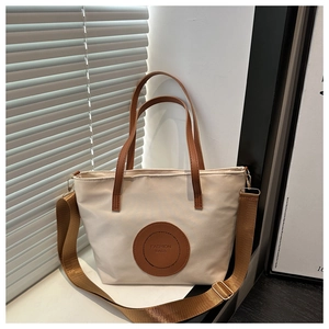 Detail of waterproof nylon tote bag with leather logo patch and detachable strap