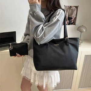 Minimalist black faux leather tote bag with gold logo and matching pouch for women