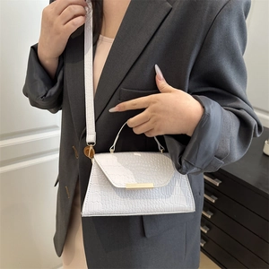Sac bandoulière blanc motif crocodile avec détails dorés porté par un mannequin