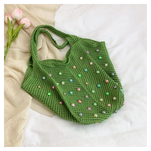 Detail of green woven tote bag featuring colorful pearl beads and hollow knit texture