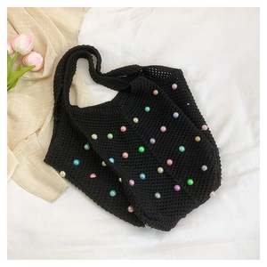 Detailed close-up of a black woven tote bag featuring vibrant rainbow pearl embellishments