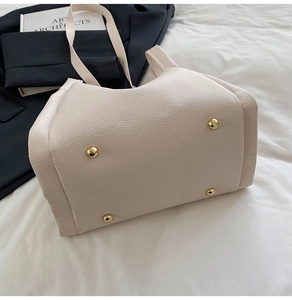 Close-up of bottom studs and pebbled leather texture on a beige tote bag