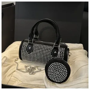Macro detail of cylinder bag featuring silver studs, chain strap, and small pouch