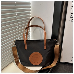 Detail of waterproof nylon tote with brown leather handles and adjustable woven strap