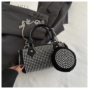 Detail of black cylinder bag with silver studs, chain strap, and mini round coin purse