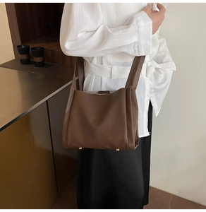 Detail of dark brown lychee leather handbag with wide shoulder strap and gold bottom studs