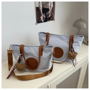 Detailed view of light blue nylon tote bags with leather straps and bear charms