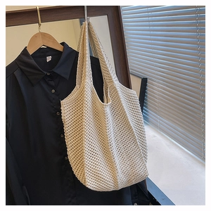 Gros plan du sac cabas en maille crème montrant la texture sur un cintre en bois