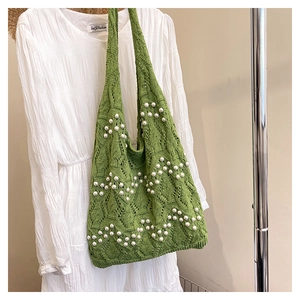 Détail du sac à bandoulière en crochet vert avec perles blanches et texture ajourée