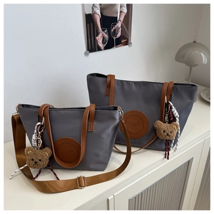 Detail of waterproof nylon tote bags with brown PU leather handles and plush bear charm