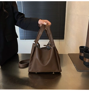 Detailed close-up of dark brown lychee-patterned tote bag with metallic base studs