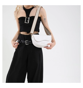 Close-up of white saddle bag with crocodile texture and fashion weave shoulder strap