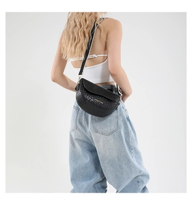 Detail of black woven texture saddle bag with gold logo and adjustable strap