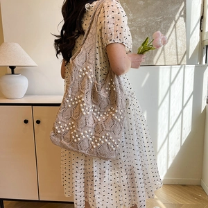 Handmade crochet tote bag with pearl wave patterns worn by a model in soft sunlight