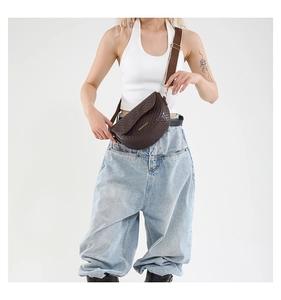 Detail of brown saddle bag with crocodile texture and wide strap on minimalist model