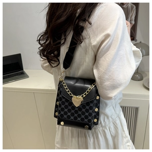 Détail de la boucle en forme de cœur doré et de la chaîne sur un sac en cuir noir