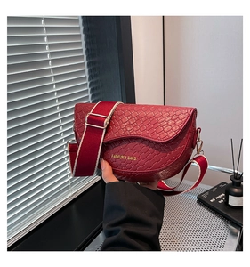 Detail of burgundy saddle bag showing woven texture and red-white wide fabric strap