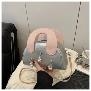 Détail du sac coquillage argenté avec texte mode et breloques perles sur soie blanche