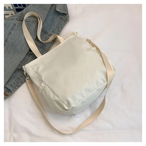 Detail view of white nylon tote bag with side drawstring pocket and adjustable shoulder strap