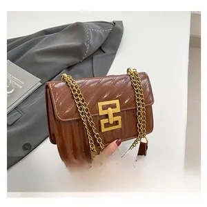 Close-up of brown quilted leather chain bag with golden geometric clasp detail