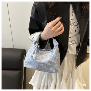 Détail d'un sac à main en dentelle bleu clair avec nœuds 3D et breloques en perles