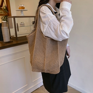 Handcrafted hollow knit tote bag in warm brown for casual shoulder wear by a model