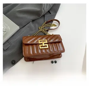 Detail view of brown quilted leather bag with golden geometric clasp and chain strap