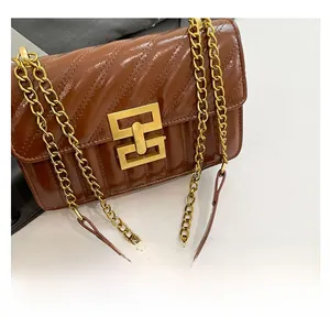 Detail of caramel brown crossbody bag with V-shaped quilting and gold square metal lock