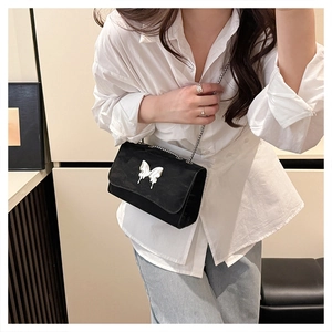 Close-up of black crossbody bag featuring a silver liquid metal butterfly buckle