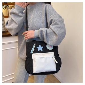 Detail der schwarz-weißen Canvas-Tasche mit blauem Stern-Patch und Trageriemen