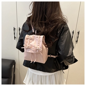 Pink mini backpack detail featuring double bow design and drawstring closure on nylon fabric