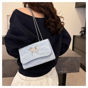 Detail of light blue crossbody bag with wrinkled texture and silver butterfly buckle