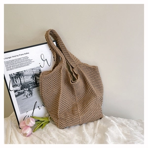 Détail du sac fourre-tout en tricot camel avec texture tissée sur lin blanc doux
