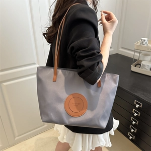 Minimalist grey nylon tote bag with leather straps and large capacity for commuting