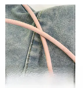 Detail of comfortable pink round shoulder strap with fine stitching on blue denim bag