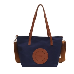 Navy blue tote bag with brown leather handles and a detachable crossbody strap